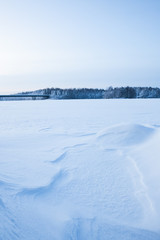 Fototapeta na wymiar Wavy wind patterns in snow at lake