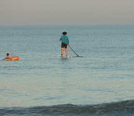 unknown paddle boarders paddling out to sea
