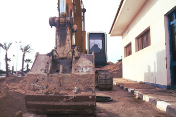 Plakat Digging machine on the construction site near the residential apartment