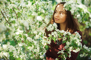Fototapeta premium young woman with clean skin near a blooming apple tree. gentle portrait of girl in spring park.