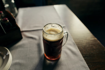 Glass of fresh dark beer close up on table