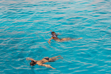 Two young women swim in the sea with snorkeling mask. Summer background