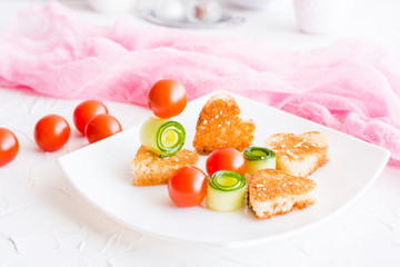 Toasts in the form of heart, cherry and cucumber on a plate. Dish served for lovers.