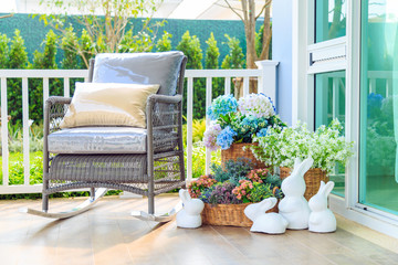 A wooden rocking chair and flowers in the basket on the wooden floor.