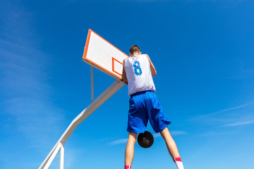 Young Basketball street player making slam dunk