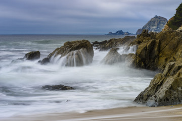 Fototapeta na wymiar foggy flowing California coastline with crashing surf and rocky cliffs