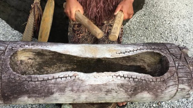 Above view of a Cook Islander man plays on a large wooden log Pate drum instrument in Rarotonga, Cook Islands.