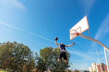 Young Basketball street player making slam dunk