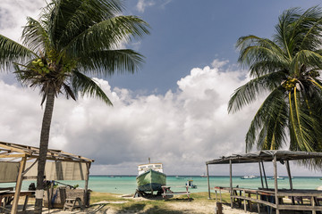 Empty tropical beach with fishing boats and palm trees