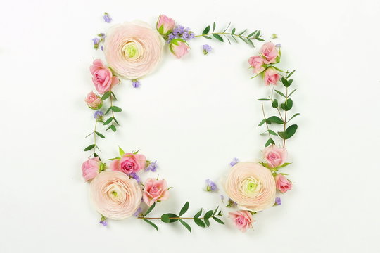 Flowers background. Wreath frame made of  pale pink roses and ranunculus  flowers and eucalyptus branches on a white background. Flat lay. top view. copy space