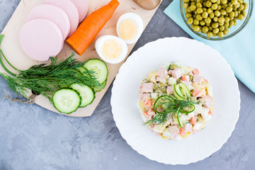 Traditional Russian salad olivier on a plate and ingredients for its preparation. Top view