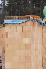  A built-in wall of a brick family house and covered with blue foil at the top.