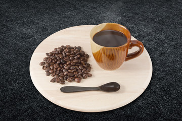 cup of hot black coffee in wooden plate