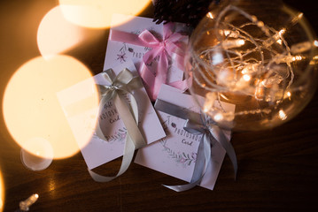 Three gift photoshoot cards with colorful ribbons near the lights garland in the vase