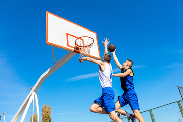Young Basketball street player making slam dunk