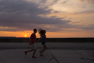 Couple in love running on the background of beautiful sunset