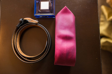 Groom’s accessories: leather belt, blue perfume and red necktie. Wedding