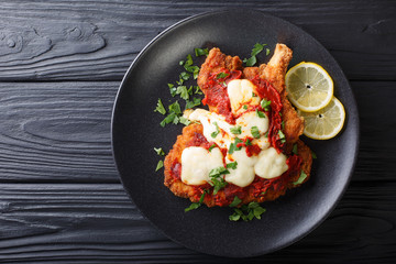 Veal Milanesa Napolitana with mozzarella cheese and tomato sauce close-up on a plate. horizontal...