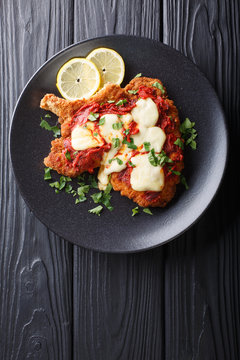 Veal Milanesa Napolitana with mozzarella cheese and tomato sauce close-up on a plate. Vertical top view
