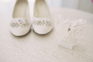 Fototapeta na wymiar Elegant women's wedding shoes with rhinestones on a light background, the fees of the bride, selective focus