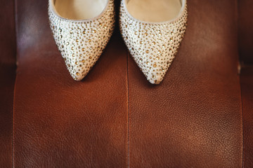 Elegant women's wedding shoes with rhinestones on a dark background, the fees of the bride, selective focus