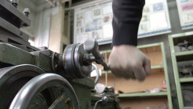 Mechanic operating old lathe machine. Rotation of the metal handle.
