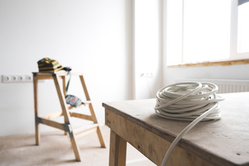 white electrical cable rests on the ladder of the goat in the interior of the apartment and repair. Electricity in the room.