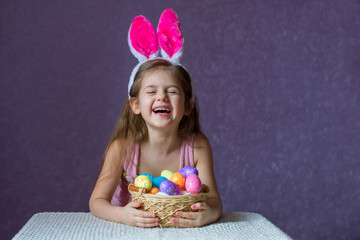 Girl holding a basket with colorful eggs and laughing