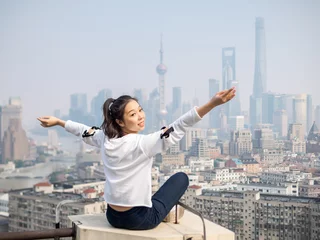 Papier Peint photo Lavable Shanghai Beautiful young brunette woman sit on top of mansion roof with blur Shanghai Bund landmark buildings background. Emotions, people, beauty and lifestyle concept.