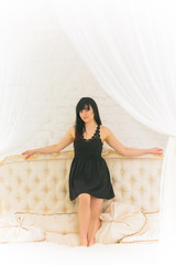 Pretty hispanic american woman in white style interior in bed at the bedroom, dressed in lace short dress. The concept of femininity and attractiveness  