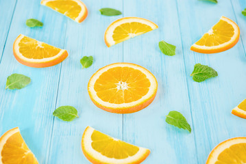 Fresh sliced oranges with pepperment leaves on light blue wood background
