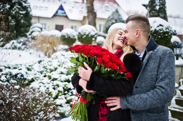 Loving couple in love at winter  day with large bouquet of 101 roses.
