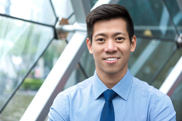 Young smiling handsome Asian businessman sitting in office lounge