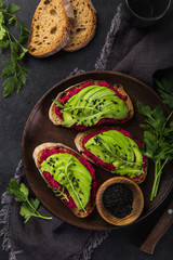 toasts with beetroot hummus and avocado on cutting board