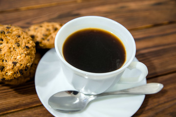 A cup of hot coffee stands on a wooden table 