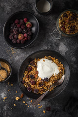 homemade granola (hazelnuts, raisin, dried cranberry, pumpkin, sesame and sunflower seeds) with yogurt in black bowl