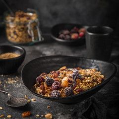 homemade granola (hazelnuts, raisin, dried cranberry, pumpkin, sesame and sunflower seeds) in black bowl.
