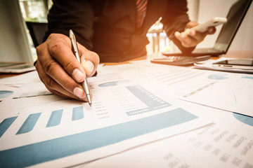 A business woman analyzing investment charts at his workplace and using his tablet.