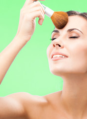Naklejka premium Woman with cosmetics brush, on green