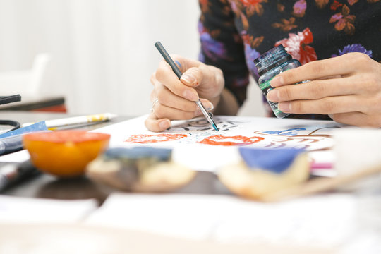 Woman make calligraphy writings, make art on a paper using pen brush and sign pen. Adult, old hands of a calligrapher woman. Lifestyle image of a design process