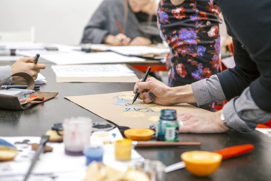 Woman make calligraphy writings, make art on a paper using pen brush and sign pen. Adult, old hands of a calligrapher woman. Lifestyle image of a design process