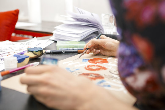 Woman make calligraphy writings, make art on a paper using pen brush and sign pen. Adult, old hands of a calligrapher woman. Lifestyle image of a design process