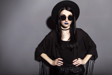 Gothic caucasian woman in dark dress on a grey neutral background. Contrast light. Sad, thoughtful...