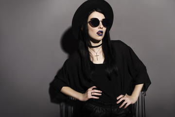 Gothic caucasian woman in dark dress on a grey neutral background. Contrast light. Sad, thoughtful...