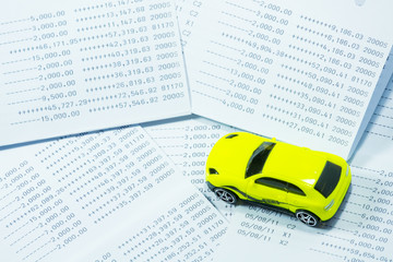 Car toy on saving statement bank book background.