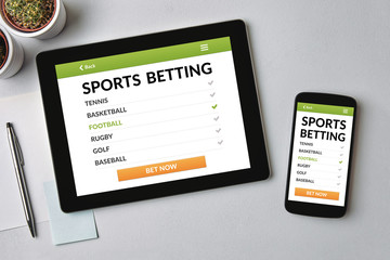 Sports betting concept on tablet and smartphone screen over gray table. All screen content is designed by me. Flat lay