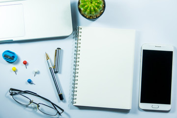 Top view of laptop, blank notebook, paper clips  and smart phone with white background and copy space.