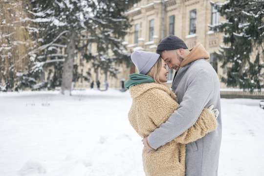 Stylish caucasian couple of man and woman waling in the european city park in winter. Cold, snowy day. Space for text