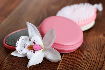 Fototapeta na wymiar Pink pumice for female feet, soap and orchid on wooden background