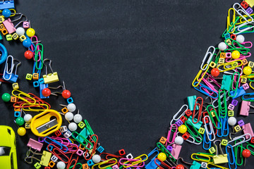 Top view of colorful office equipment with copy space on black chalkboard background. Education concept.